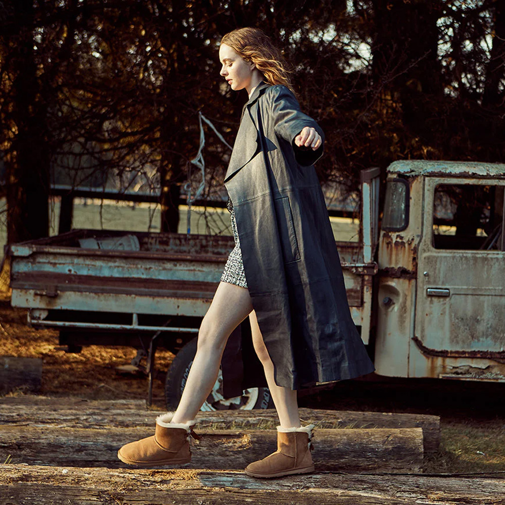 Woman in long coat posing while wearing UGG boots in an Autumn scene