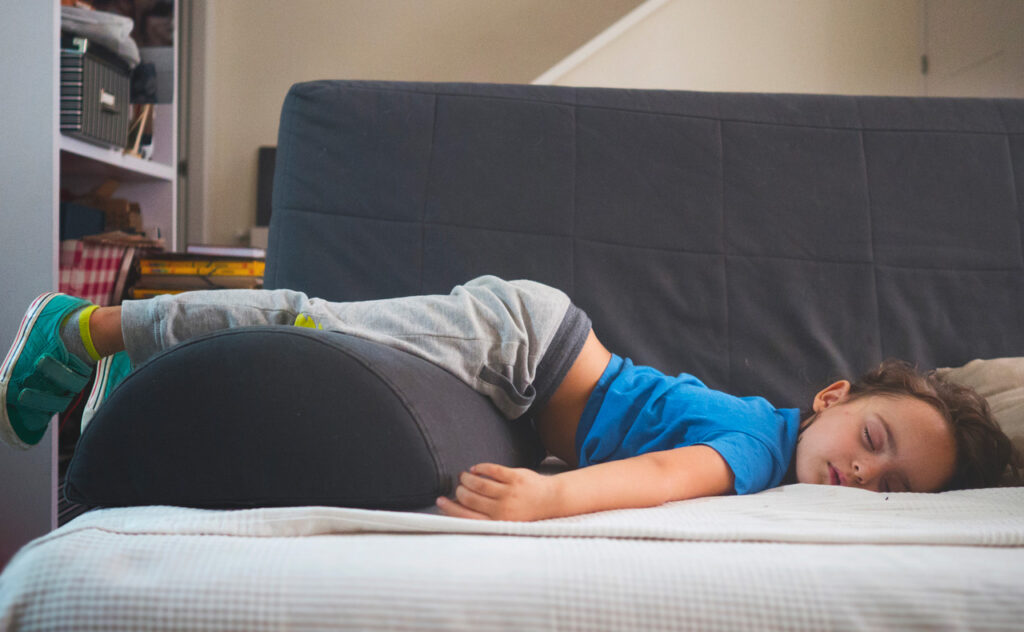 Photograph of a little girl asleep on a sofa after a day of school