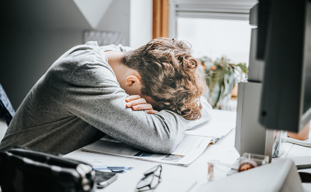 Stressed teen with head on desk.