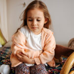 Photo of young girl having stomach pain in the house. Healthcare and illness concept.