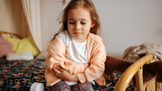 Photo of young girl having stomach pain in the house. Healthcare and illness concept.