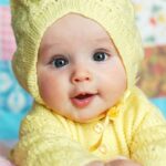 Cute baby girl in yellow knit beanie and cardigan