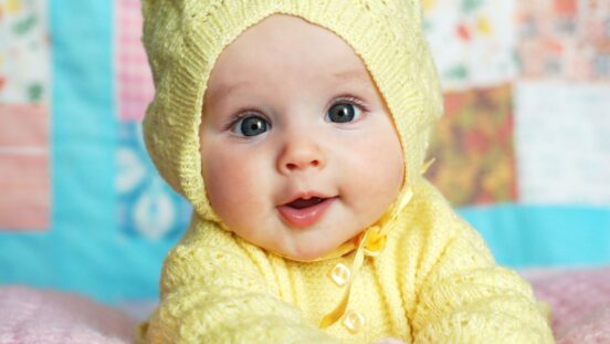 Cute baby girl in yellow knit beanie and cardigan