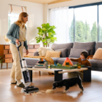 Lifestyle shot of woman using a Tineco wet dry vaccum cleaner to deal with an upturned dog ball with a dog and child nearby