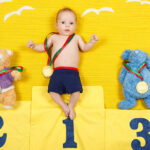 Portrait of a cute child is standing on a place podium in first place. Handsome boy is cheering and standing on victory podium with medal.