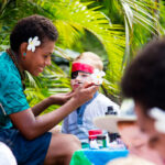 Young boy getting his face painted by beautiful hotel staff at Outrigger Fiji