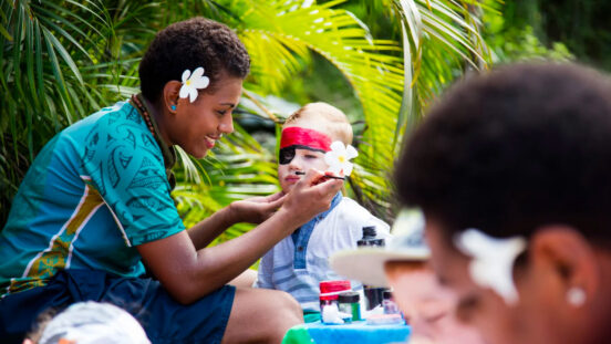 Young boy getting his face painted by beautiful hotel staff at Outrigger Fiji