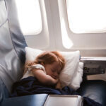 Litte girl (2-3) sleeping in business class airplane seat