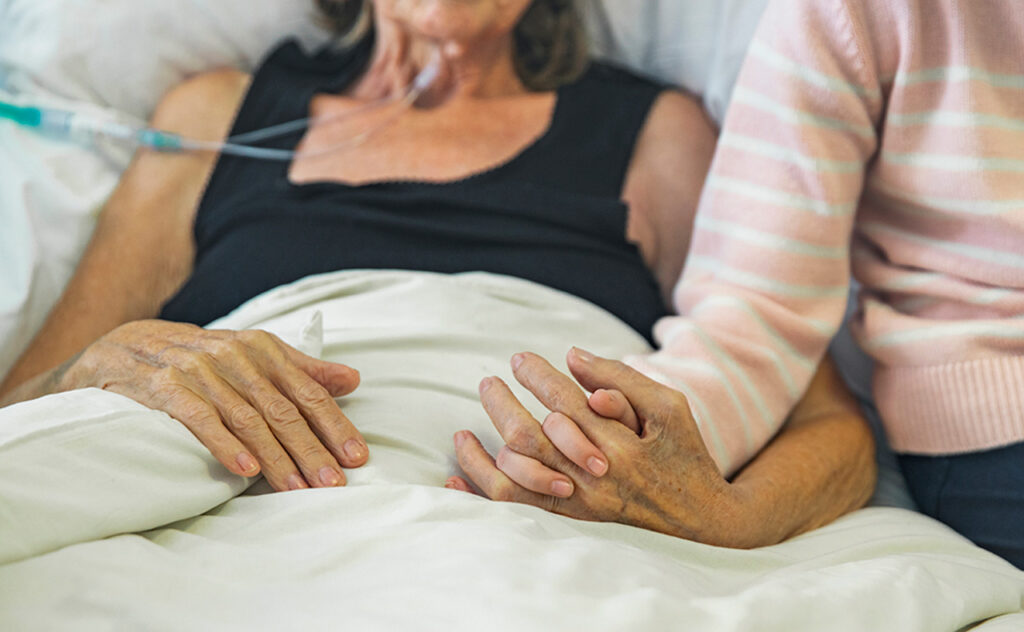 Young girl holds the hand of her ill grandmother 
