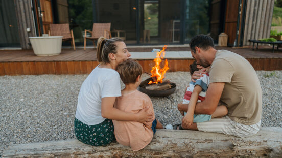 Photo of a young loving family, spending quality time together at the end of the busy week in front of their vacation home