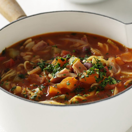 Close up of a delicious looking minestrone soup in a white saucepan