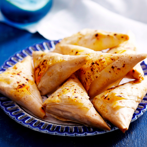 Several cheese, tomato and olive triangles piled on a blue plate