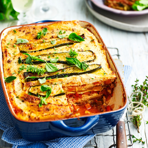 Blue pan containing a tasty looking lasagne topped with zucchini and fresh herbs