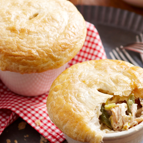 Image shows two chicken, leek and asparagus pot pies, one that has been cut into