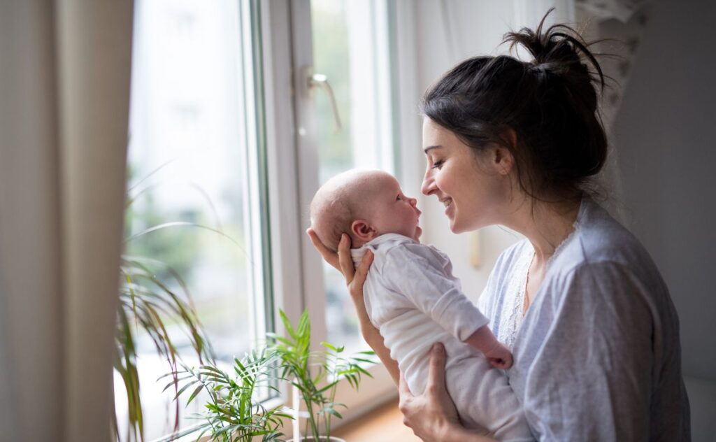 Loving and affectionate mother holding newborn baby indoors at home.