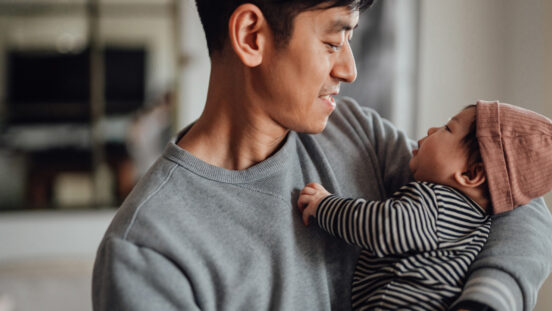 Smiling Asian father shot holding his baby daughter looking at each other. Happy family portrait. Father sharing parental responsibility.