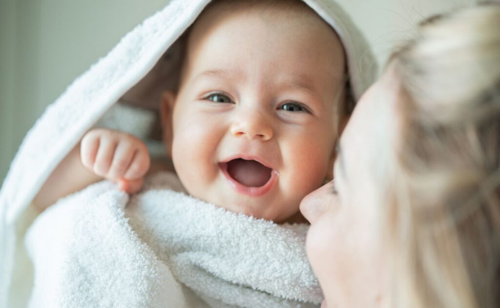 Mother wrapping smiling baby in a towel