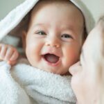 Mother wrapping smiling baby in a towel