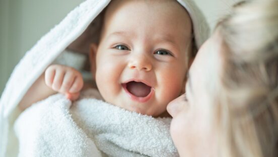 Mother wrapping smiling baby in a towel