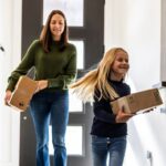 Young girl and mother bringing delivery package into home