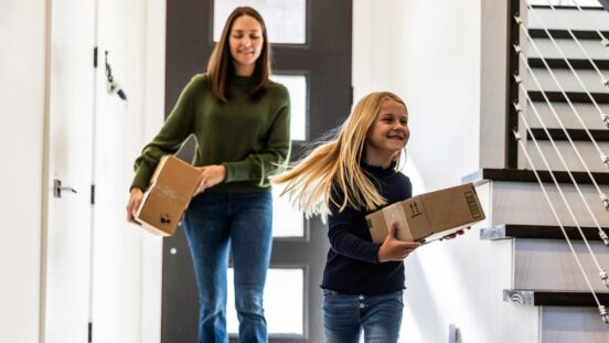 Young girl and mother bringing delivery package into home