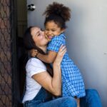 Mother kissing daughter on the cheek before school