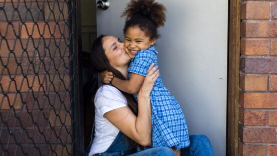 Mother kissing daughter on the cheek before school