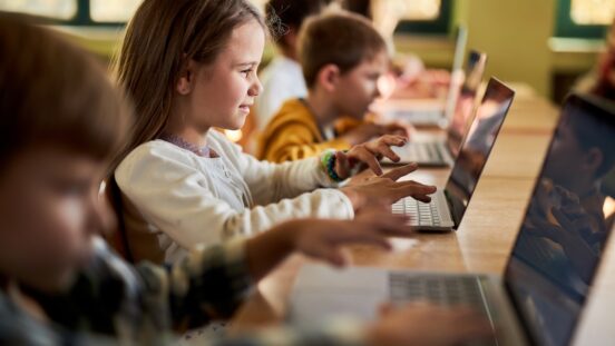 A class of primary school students using laptops.