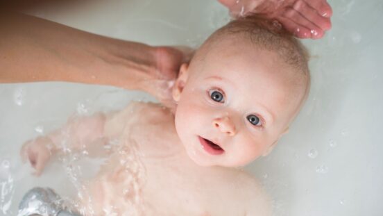 Mother washing baby in a bath