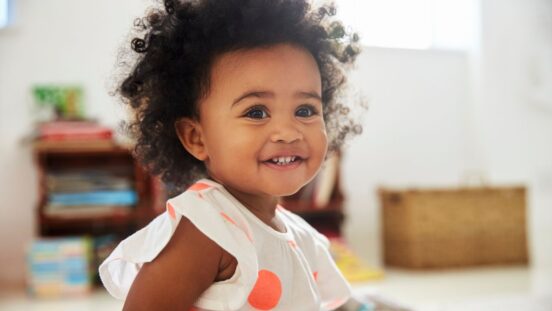 Happy Baby Girl Playing With Toys In Playroom